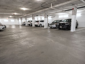 Eine Parkgarage mit mehreren Wagenreihen und Betonpfeilern.