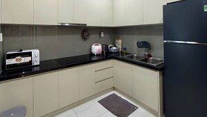 Una cocina moderna con armarios blancos, encimera negra, pileta de acero inoxidable y refrigerador negro.