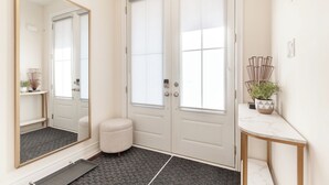 A hallway with a large mirror, double doors, a small stool, a marble console table, and a potted plant. - Modern Family Haven | 3BR Upstairs + Private Lower Suite (Richmond Hill)
