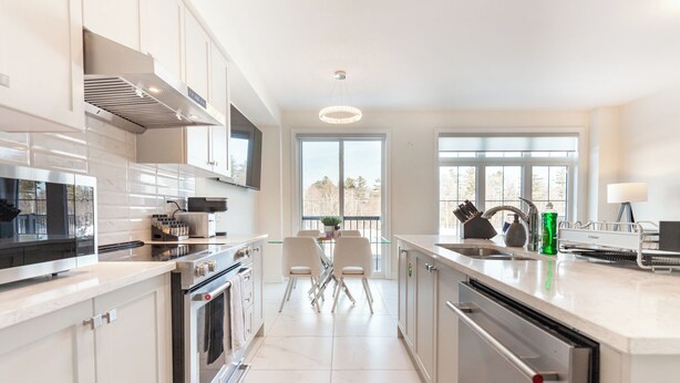 A modern kitchen with a central island, stainless steel appliances, and large windows providing natural light. - Modern Family Haven | 3BR Upstairs + Private Lower Suite (Richmond Hill)