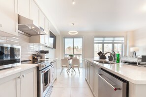 Una cocina moderna con una isla central, electrodomésticos de acero inoxidable y ventanas amplias que ofrecen luz natural.