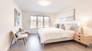 A bedroom with a bed, bedside table, chair, and a window with a view. - Modern Family Haven | 3BR Upstairs + Private Lower Suite (Richmond Hill)