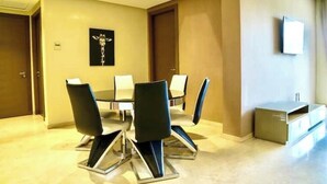 Una sala conferenze con un tavolo rotondo, sei sedie e un televisore a parete.