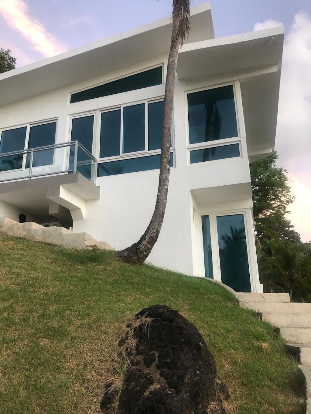 Een modern huis met twee verdiepingen, grote ramen en een gebogen dak.