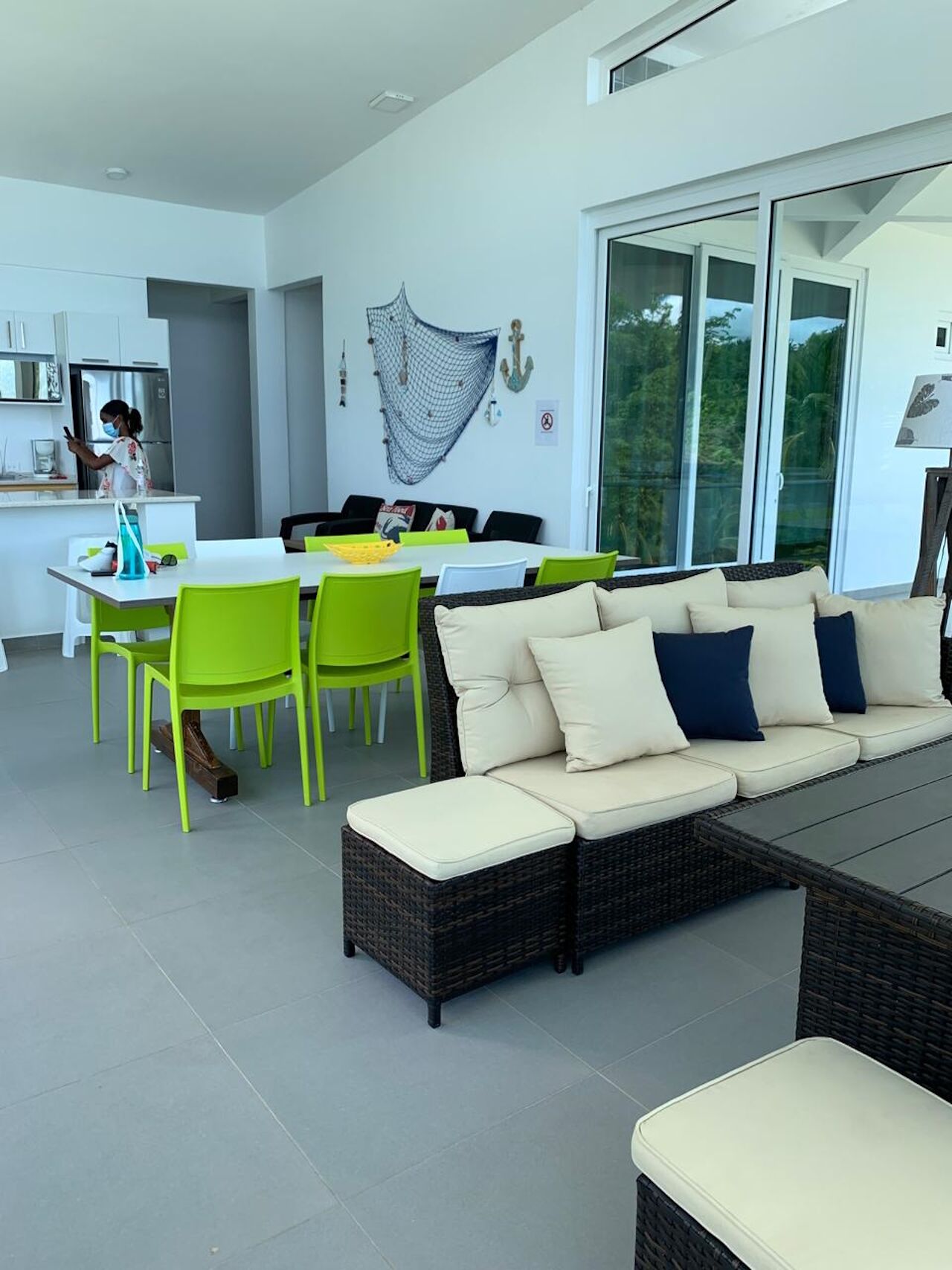 Un espace de vie moderne comprenant un canapé, des fauteuils, une table à manger et un coin cuisine.