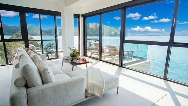 A modern living room with a large sofa, a coffee table with a chess set, and a view of the sea through large windows. - The Waterfront Studio (Busuanga)