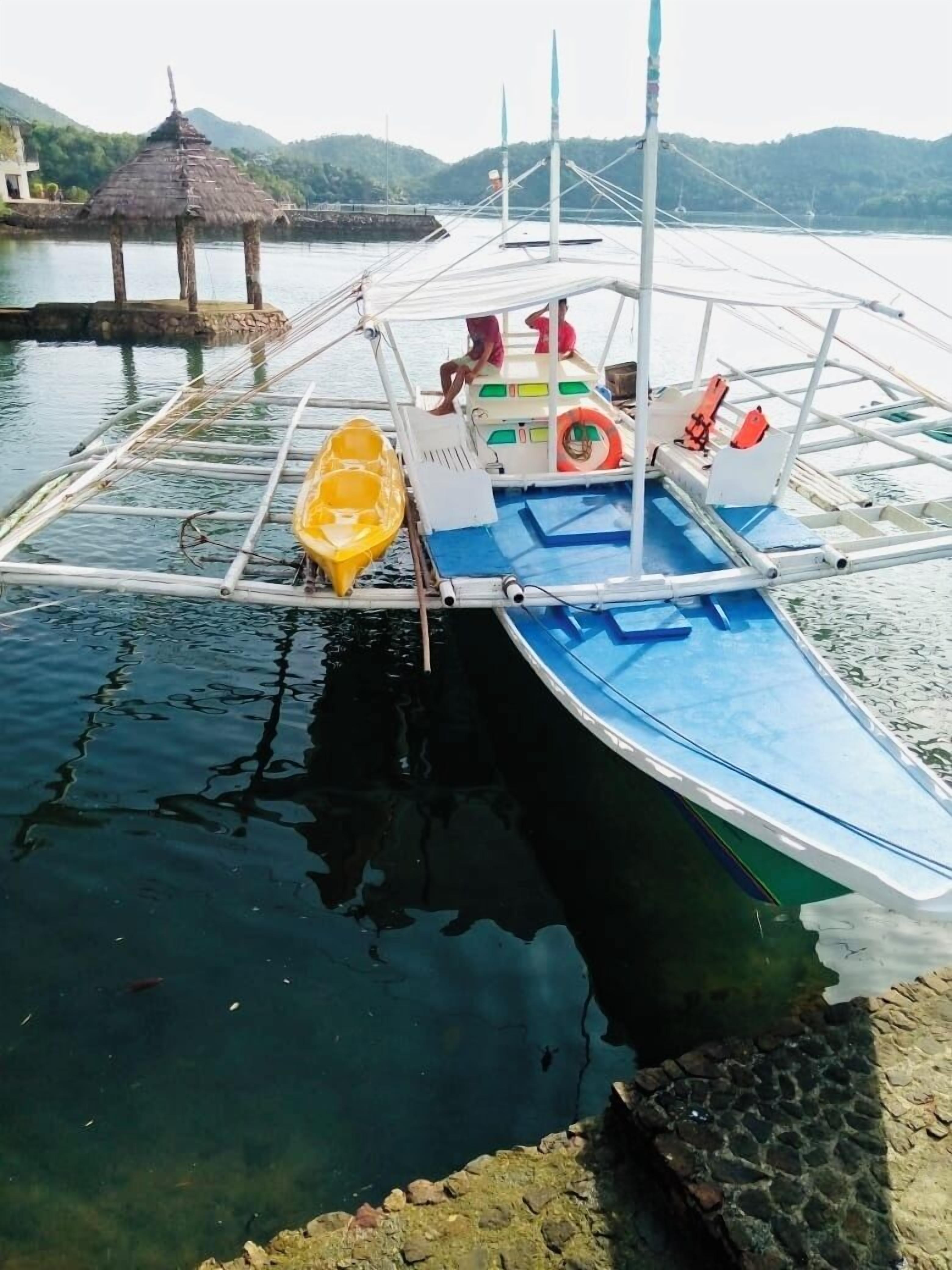 A boat docked at a pier with a thatched roof structure in the background.