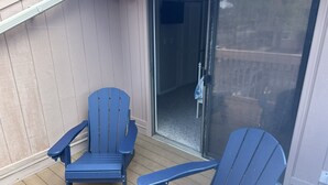 Two blue Adirondack chairs on a wooden deck with a glass door leading to a covered area. - The Blue Turtle: 3-bedroom, 2-bath MB townhouse w/ 5 min walk to the beach (Myrtle Beach)