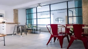 Et moderne køkken med et stort vindue, et spiseområde med røde stole og et hvidt flisegulv.