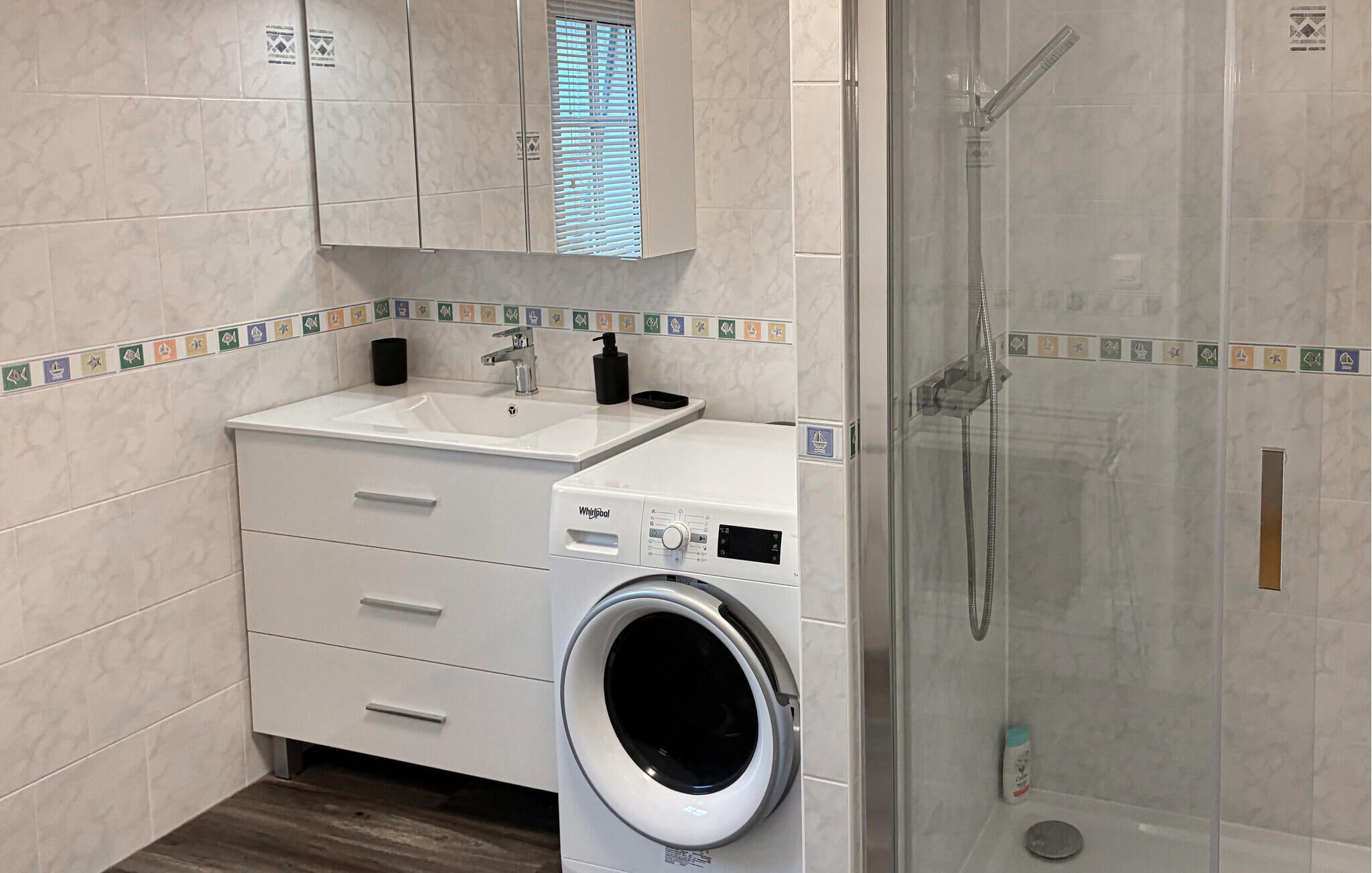 Ein modernes Badezimmer mit Waschmaschine, Waschbecken und einer Duschkabine.
