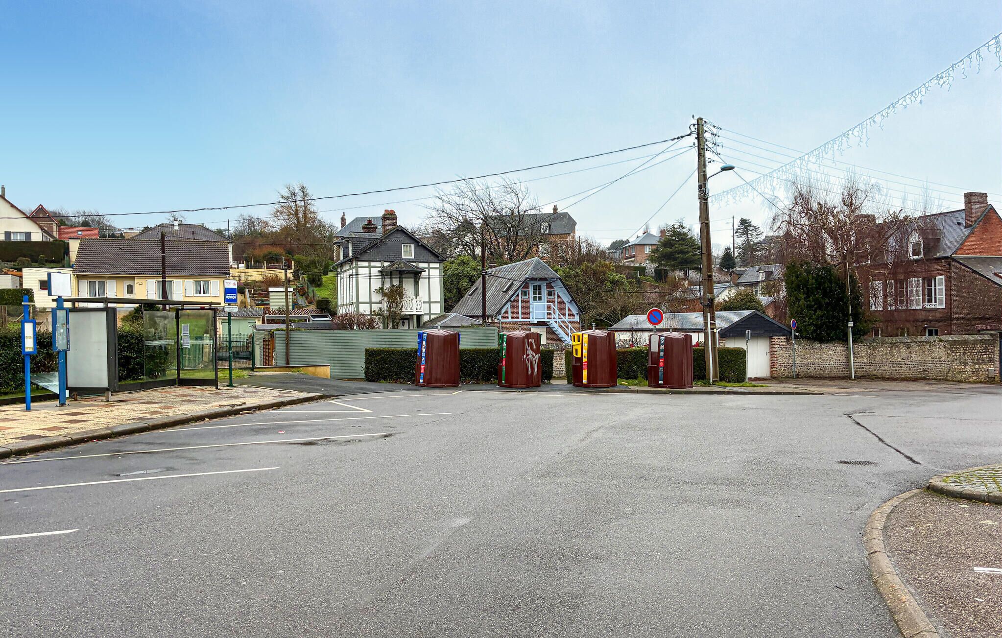 Straßenansicht mit Bushaltestelle, einem verschlossenen Eingang und Wohnhäusern.