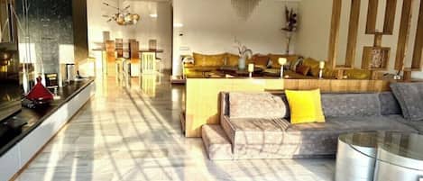 A spacious living area with a sofa set, a coffee table, and a modern chandelier.