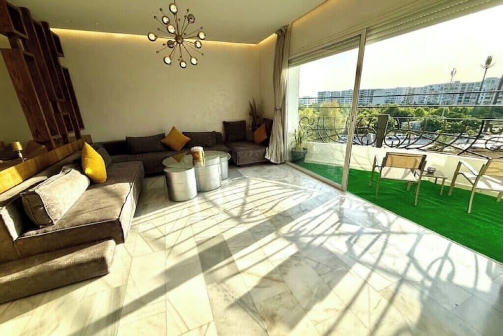 A modern living room with a sofa, coffee table, and a balcony with a view of the city.