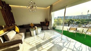Ein modernes Wohnzimmer mit einer Couch, einem Couchtisch und einem Balkon mit Blick auf die Stadt.