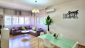 A modern living room with a sofa, a glass dining table, and a chandelier. - AR Apparts (city center -Wifi 100 Mb) (Fès)