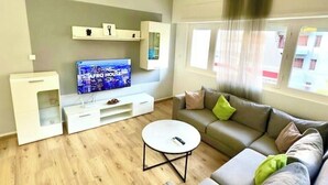 En moderne stue med et fladskærms-tv, en sofa, et sofabord og indbyggede reoler.