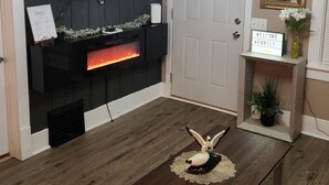 Ein Wohnzimmer mit Kamin, Fernseher, einer Chandelieber und einem Couchtisch.