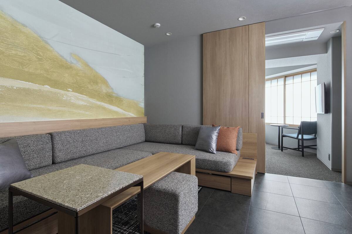 A modern living room with a sectional sofa, a wooden coffee table, and a large abstract painting on the wall.