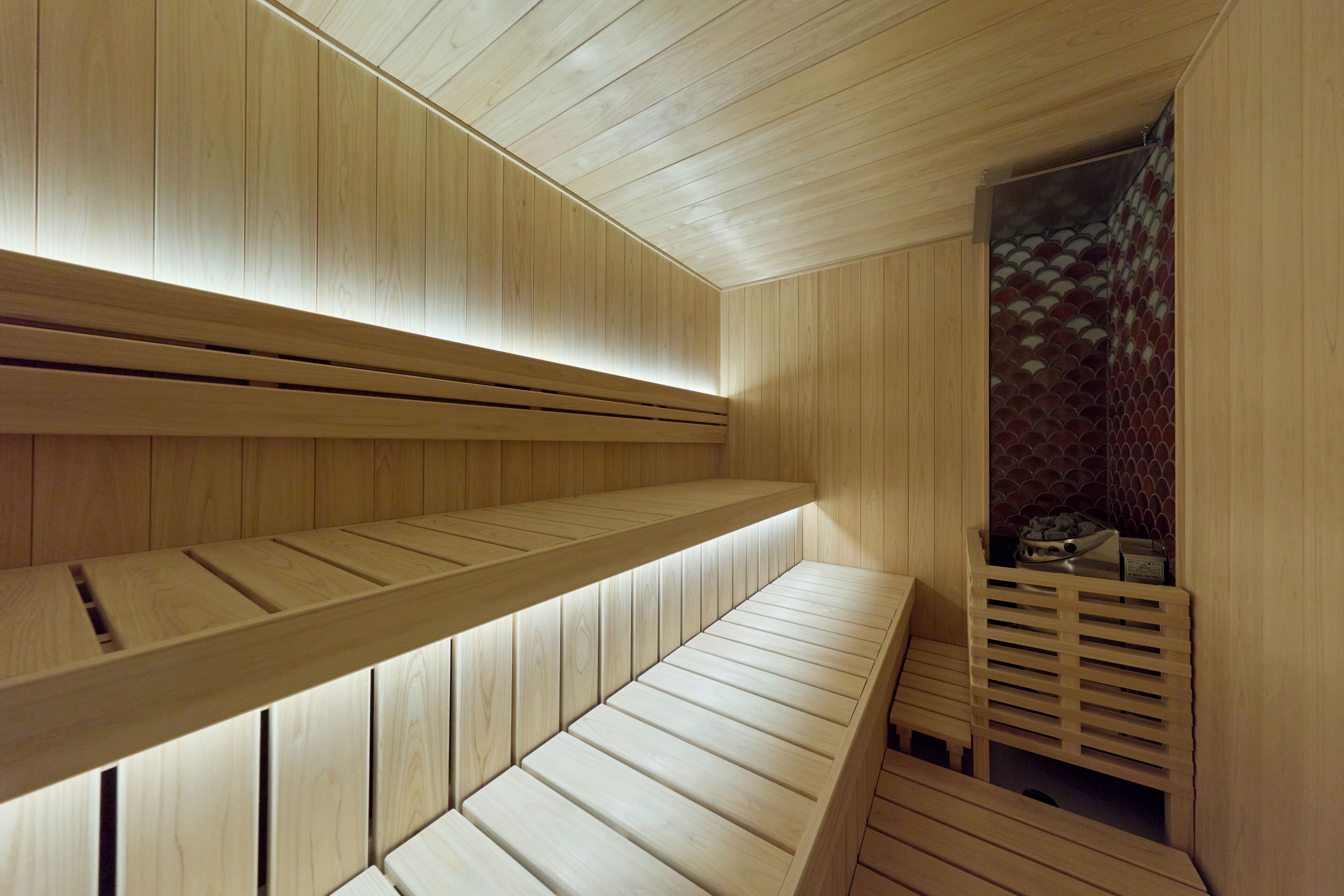 Una sauna de madera con bancos y pared de azulejos.