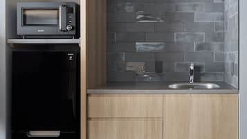 A kitchen with a microwave, refrigerator, and a sink with a modern faucet.
