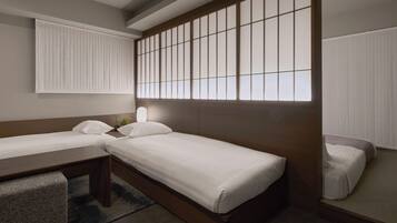 A hotel room with two beds, a desk, and a large window with blinds.