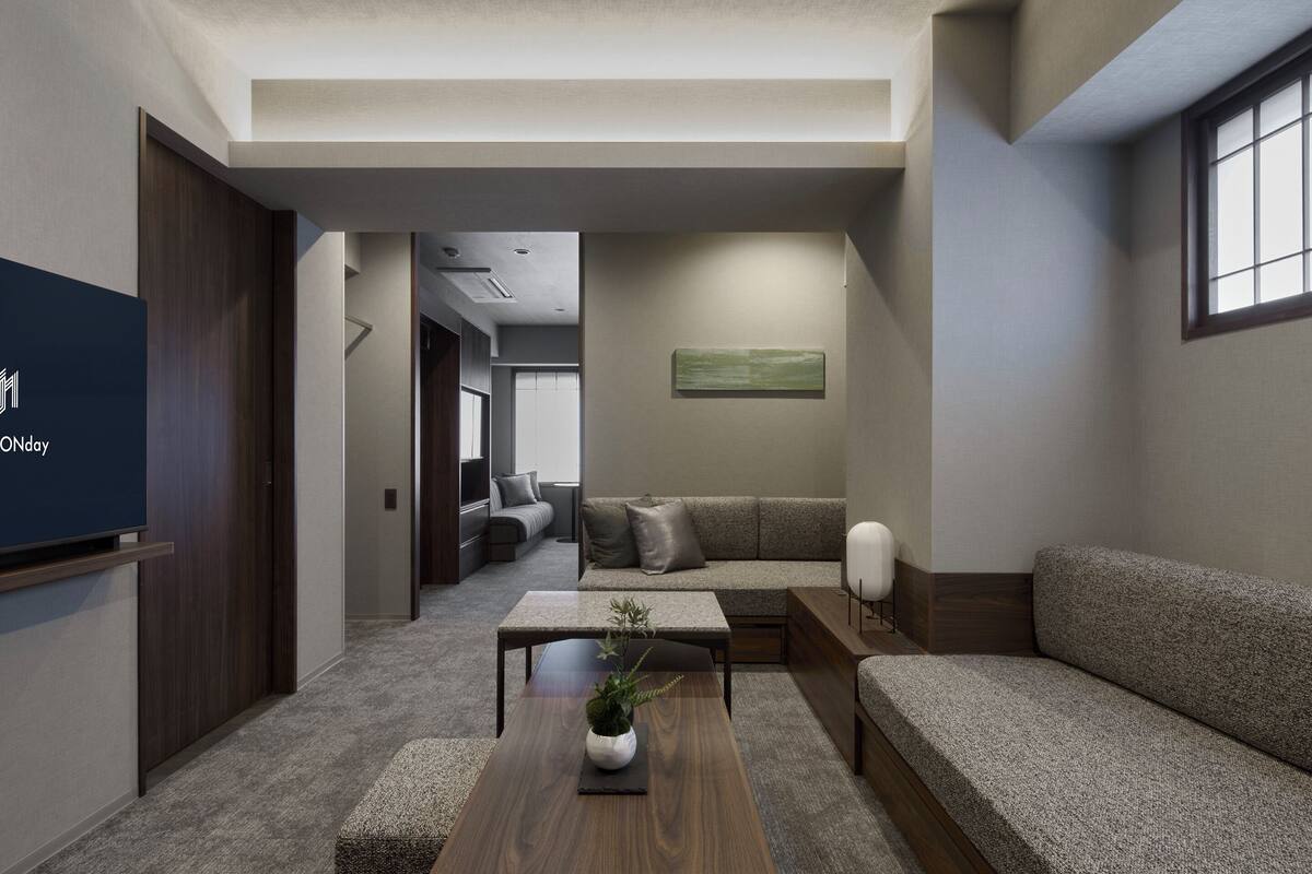 A modern living room with a sofa, a coffee table with a plant, a television, and a painting on the wall.