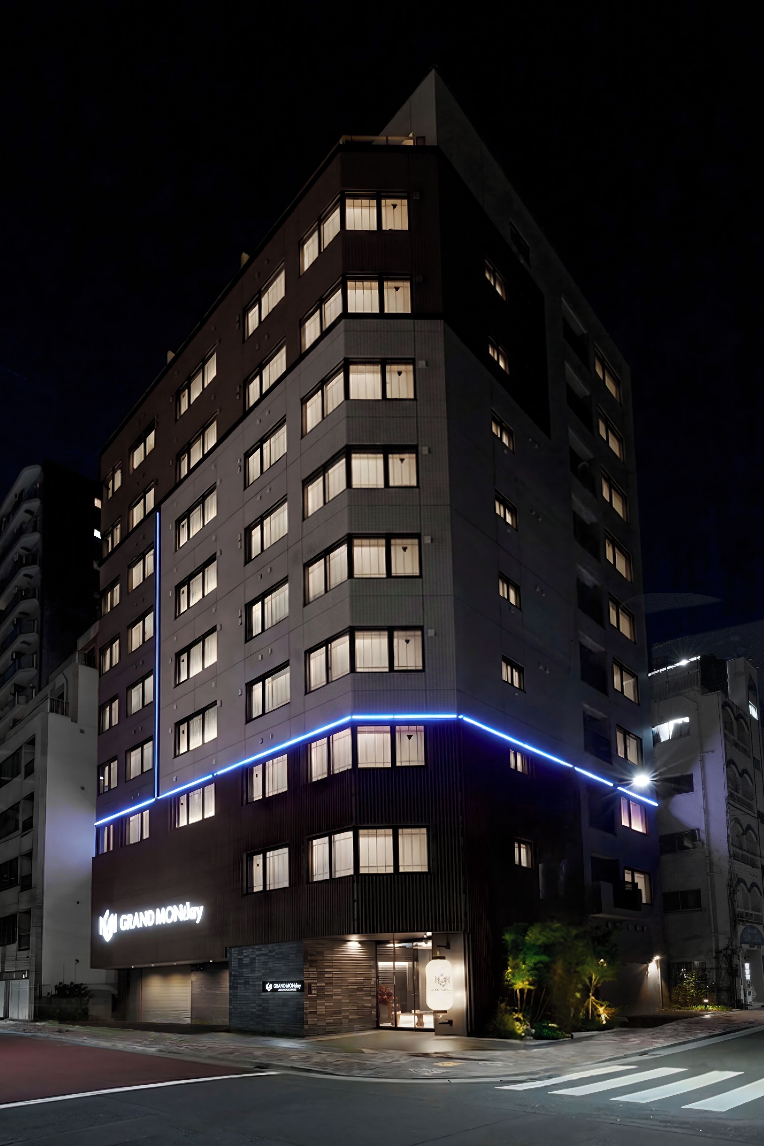 Ett hotell med flera våningar, upplyst skyltning och en framträdande entré.
