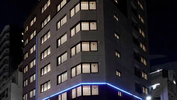 Ett hotell med flera våningar, upplyst skyltning och en framträdande entré.