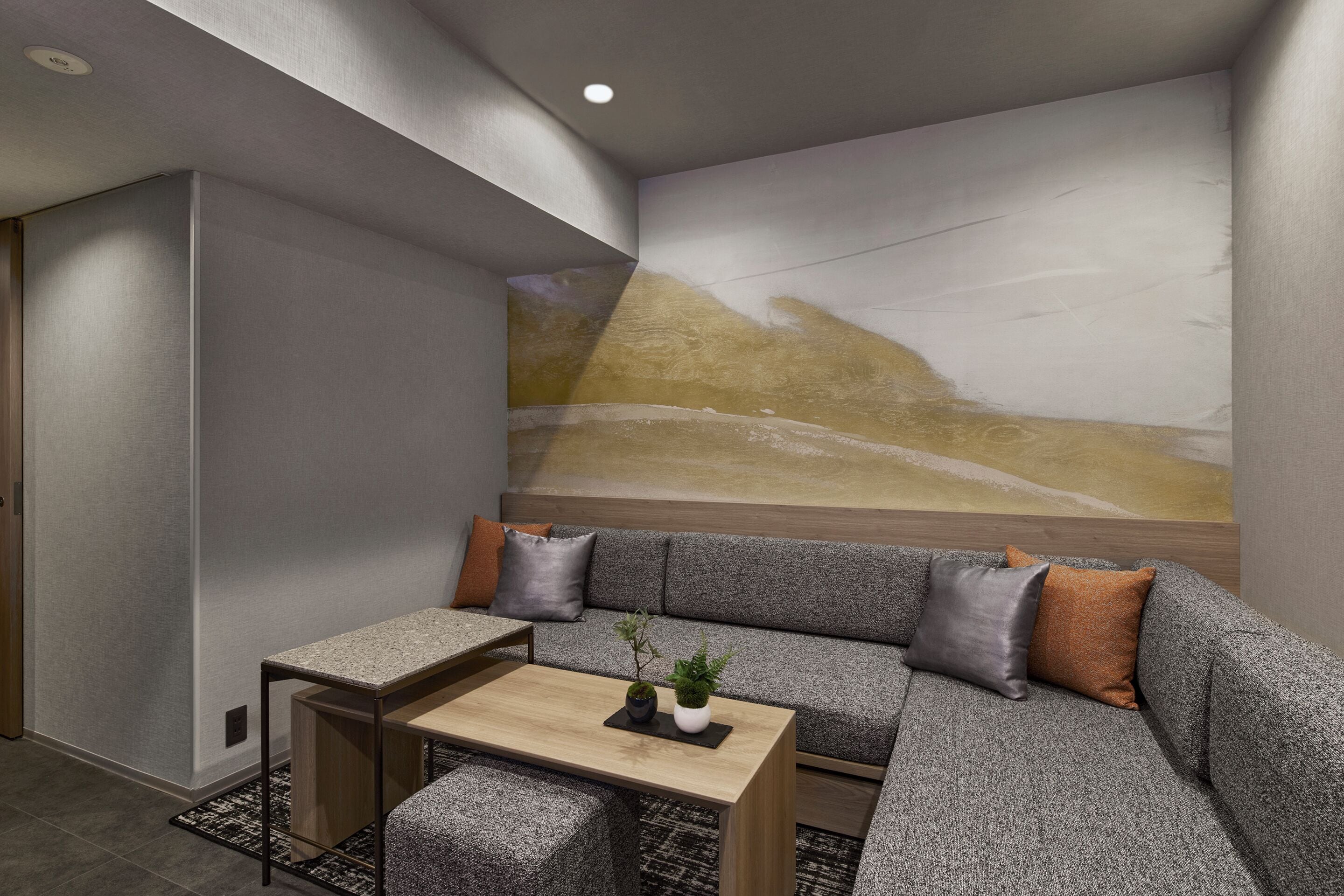 A modern room with a sectional sofa, a small table, and a wall mural.