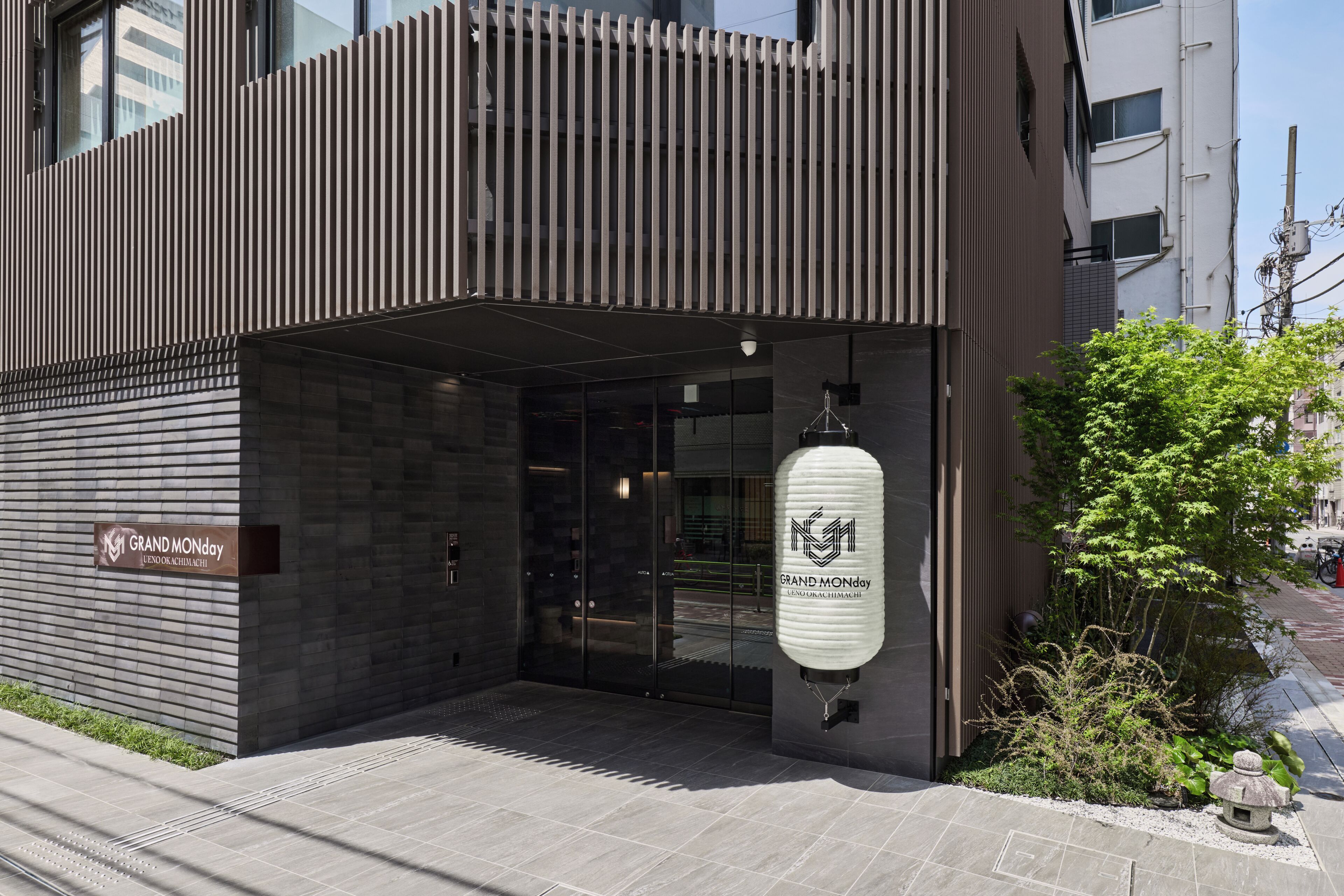 A modern building with a sign reading 'GRAND MONDAY' and a hanging lantern.