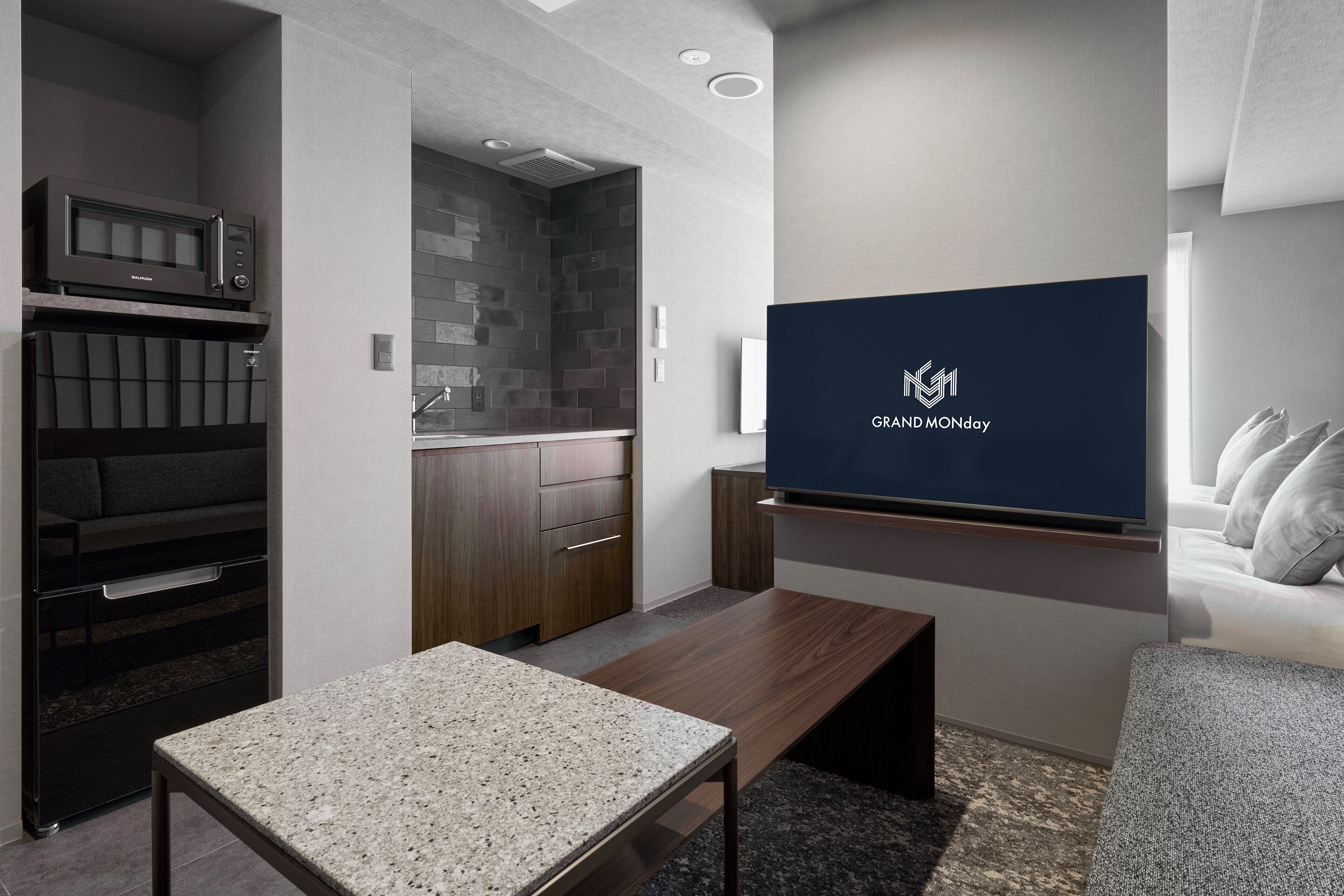 Ein modernes Hotelzimmer mit Küchenzeile, einem Flachbildfernseher, einer Sitzecke und einem großen Fenster.
