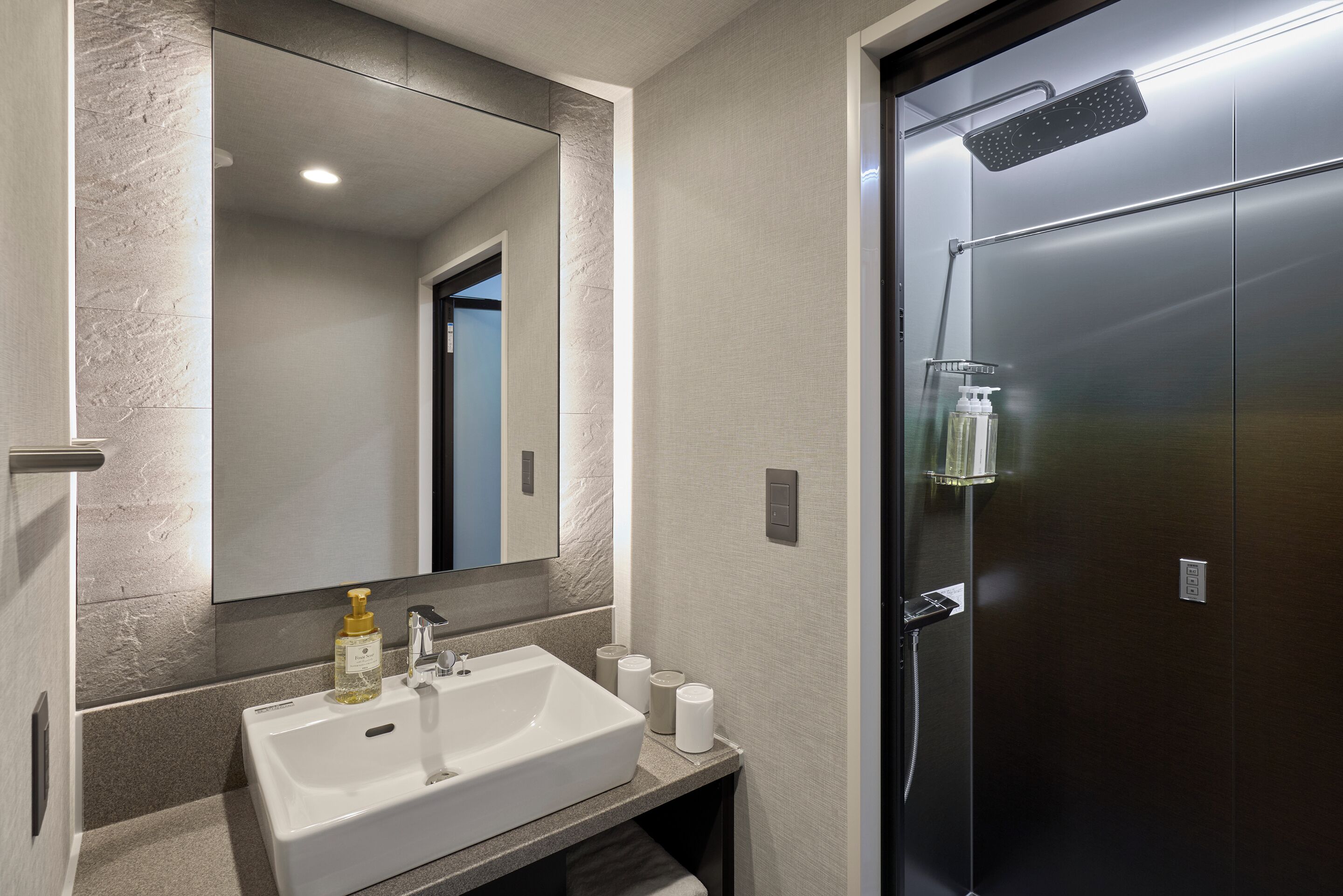 A modern bathroom with a large mirror, a sink, and a shower.