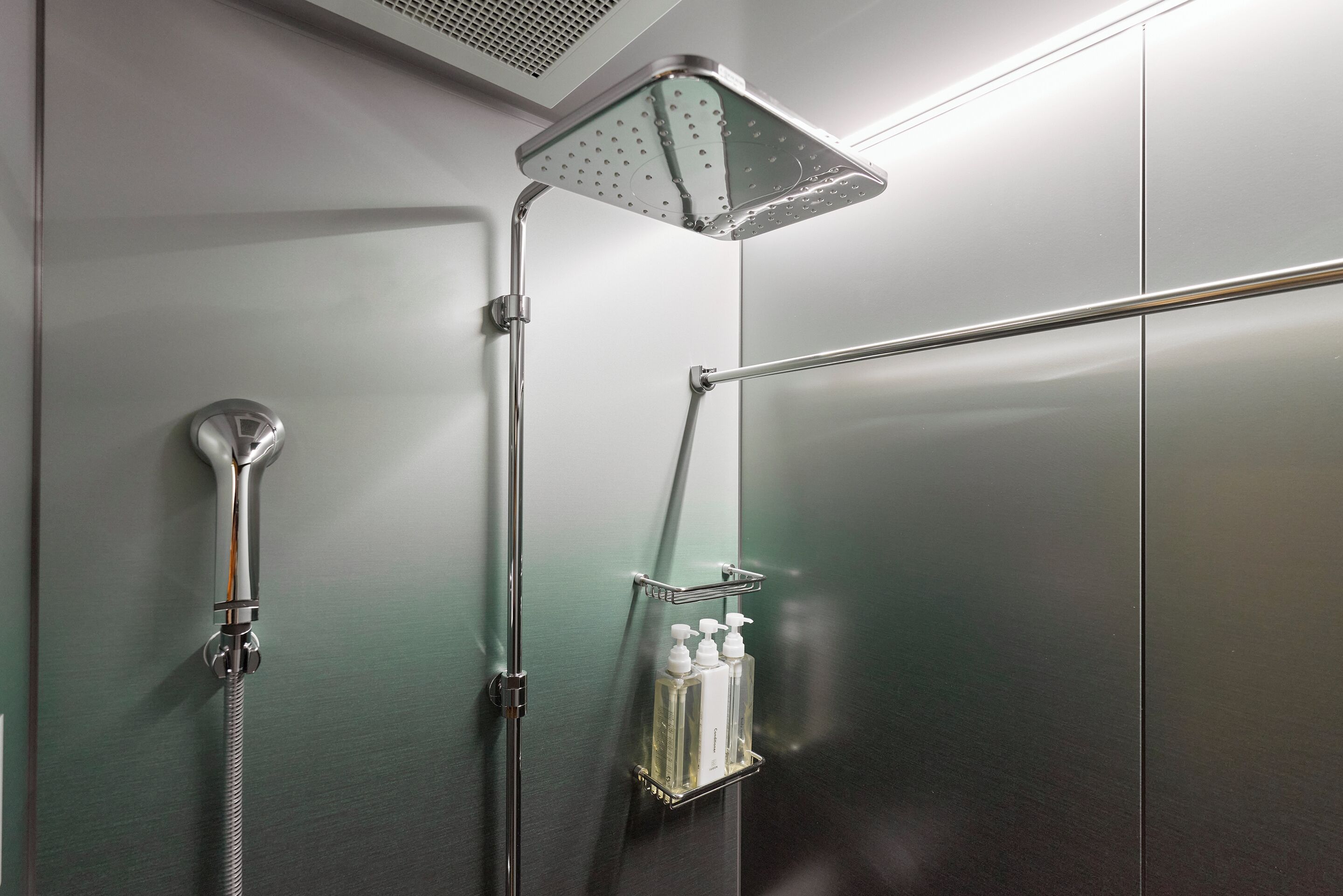 A modern shower with a handheld showerhead, a fixed showerhead, and a soap dispenser.