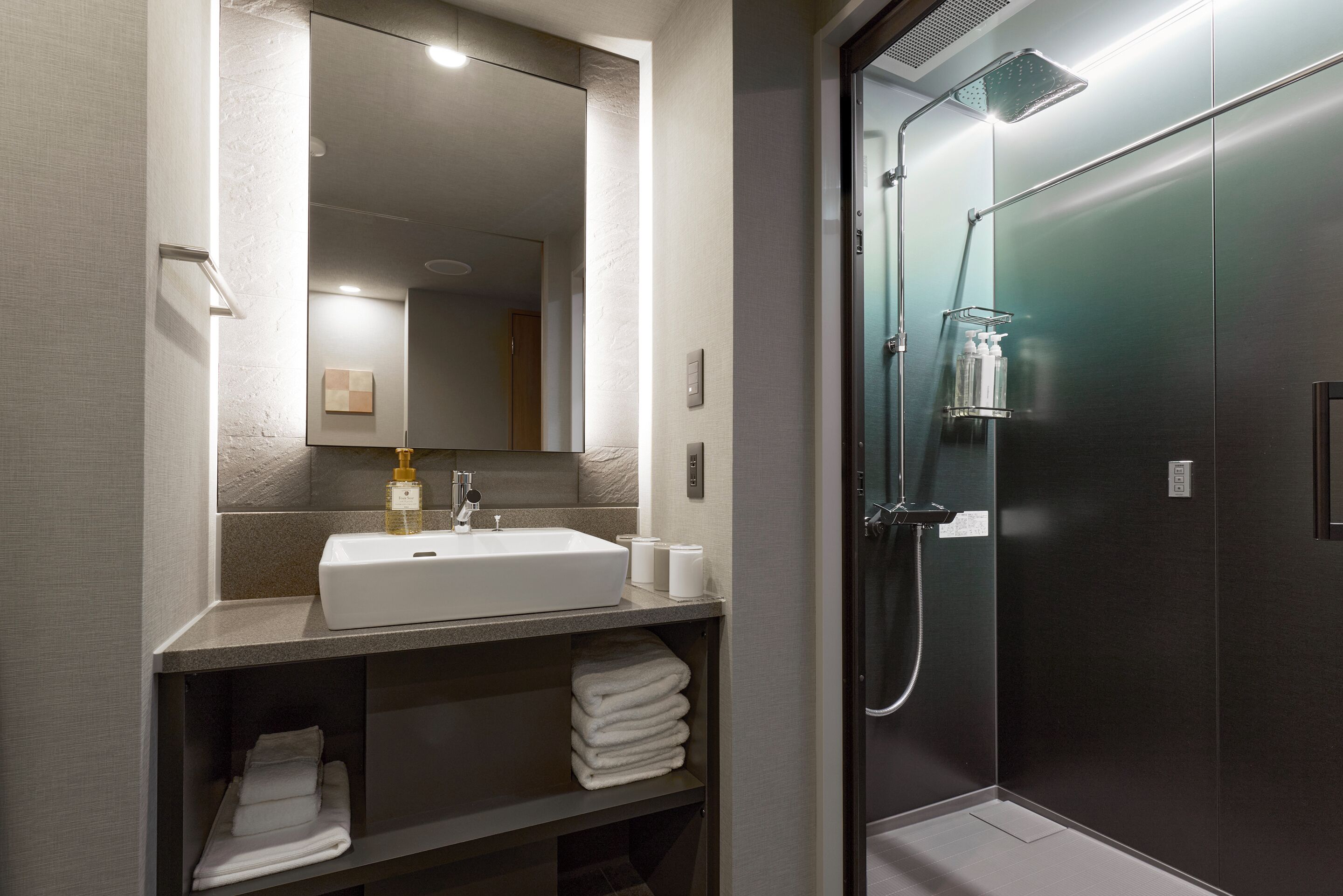 A modern bathroom with a sink, mirror, and shower.