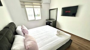 A modern hotel room with a bed, a TV mounted on the wall, and a window with blinds. - AR Apartments downtown (Wifi 200 Mb) (Fès)