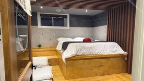 A compact room with a bed, a small window, and a wooden bench. - Niagara Retreat Center by Taiji Qi Yoga (niagara Falls)