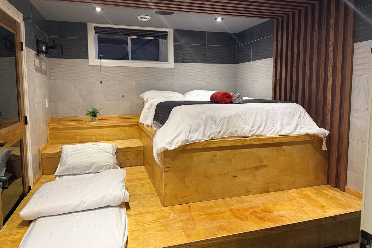 A compact room with a bed, a small seating area, and a window.