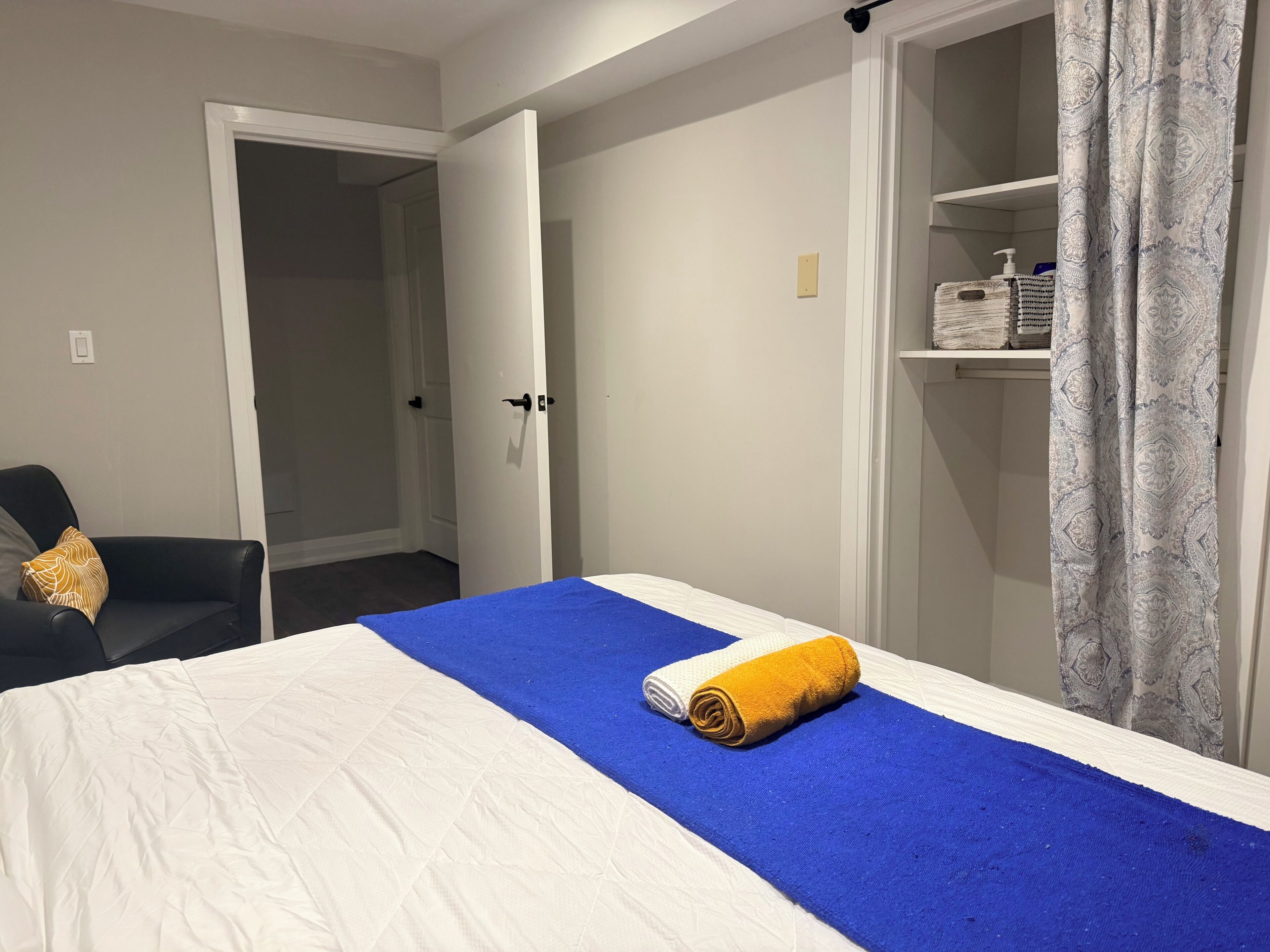 Et hotelværelse med seng, stol, garderobeskab og badeværelse.