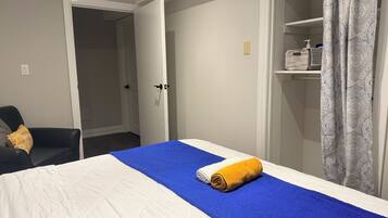 Et hotelværelse med seng, stol, garderobeskab og badeværelse.