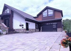 Ein modernes, zweistöckiges Haus mit Garage, Stein Fundament und Auffahrt.