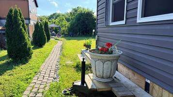 A paved pathway leading to a house with a potted plant on a wooden bench.
