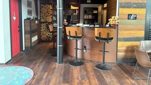 A modern bar area with wooden bar stools, a red door, and a bookshelf filled with books. - Niagara Retreat Center by Taiji Qi Yoga (niagara Falls)