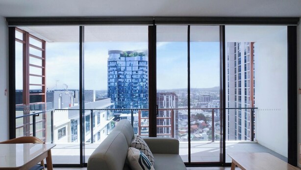 Un appartement moderne doté de grandes fenêtres du sol au plafond, d’un canapé et d’une table à manger.