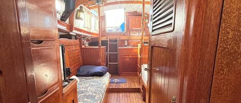 A narrow wooden corridor with a bunk bed, a small table, and a window.