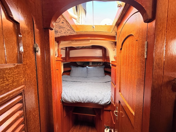 A narrow wooden cabin with a bunk bed, a skylight, and a small window. - Anchored sailboat stay in beautiful St. Augustine (St. Augustine)