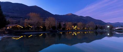 A calm lake reflecting buildings and mountains.