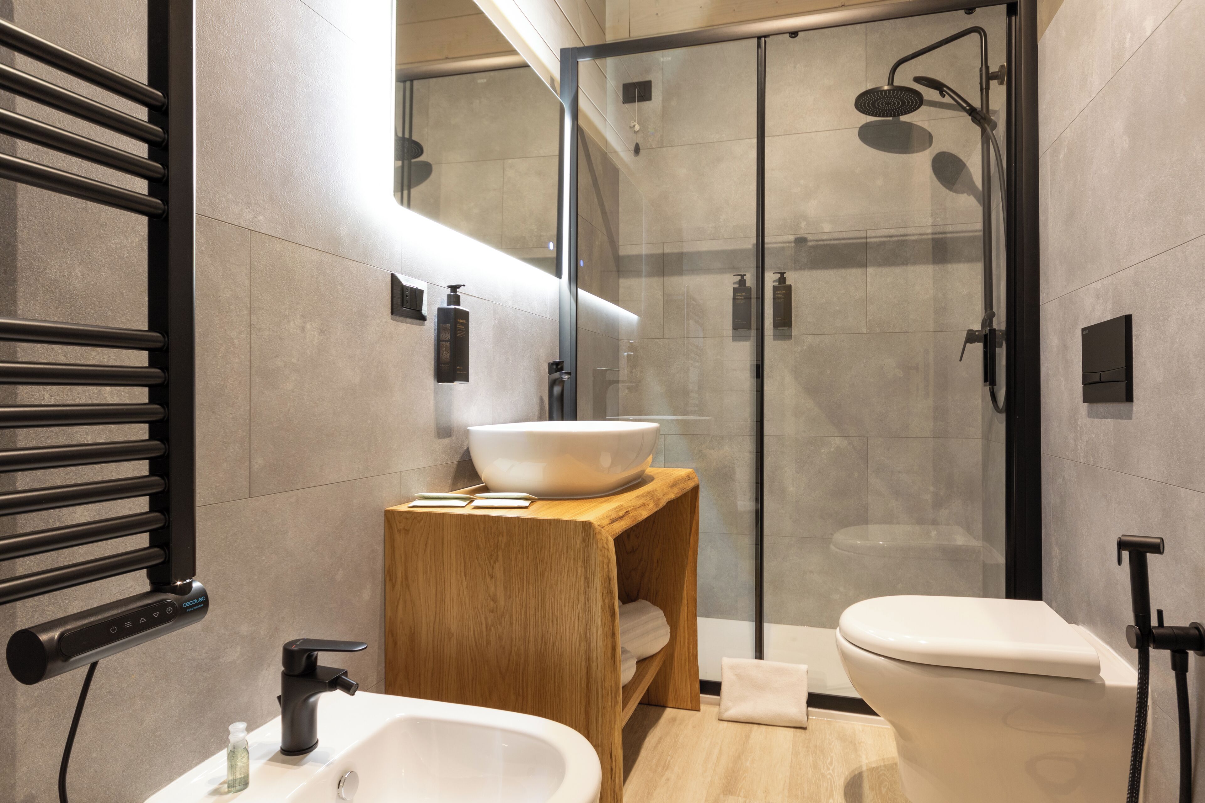 Ein modernes Badezimmer mit einer begehbaren Glasdusche, einem Holzwaschtisch und einem weißen Waschbecken.