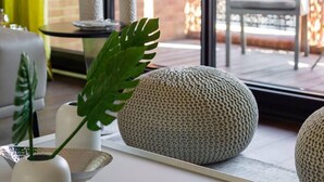 A modern interior with a minimalist design, featuring a white console table, textured spherical objects, and a potted plant. - Modern 3-bed Residence in Westminster With Concierge (London)
