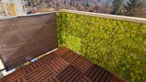 Una terrazza sul tetto con un pavimento di legno e un muro verdeggiante.