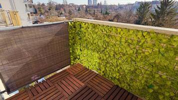 Terraza en la azotea con cubierta de madera y pared verde y frondosa.